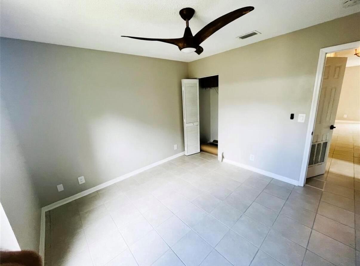 An empty bedroom features light-colored tile flooring, a ceiling fan, and a closet with louvred doors — 47 SE 13th Street # 2, Dania Beach FL 33004, DANIA BEACH, FL