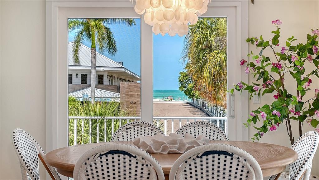 A dining room with a round wooden table, white woven chairs, and a view of the ocean — 6327 GULF DRIVE, HOLMES BEACH, FL