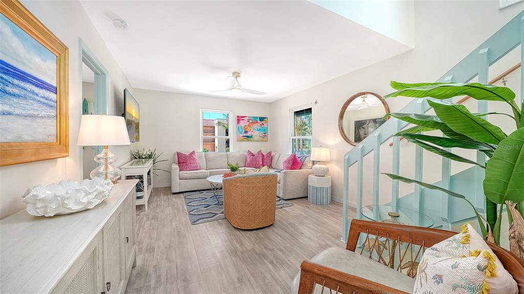 A living room features light wood flooring, a sectional sofa, and a staircase with railings — 6327 GULF DRIVE, HOLMES BEACH, FL