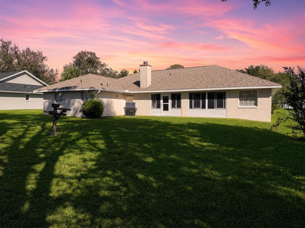The exterior rear view of a single-story house features a screened porch and chimney — 5402 SW 85TH STREET, OCALA, FL