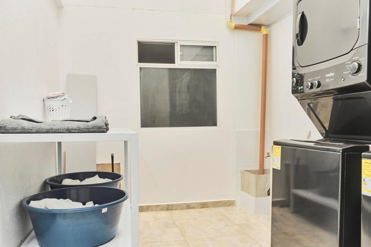 A laundry room with a stacked washer and dryer, a white shelf, and tile flooring — Carrera 47 Numero 64 45, 00000, FL