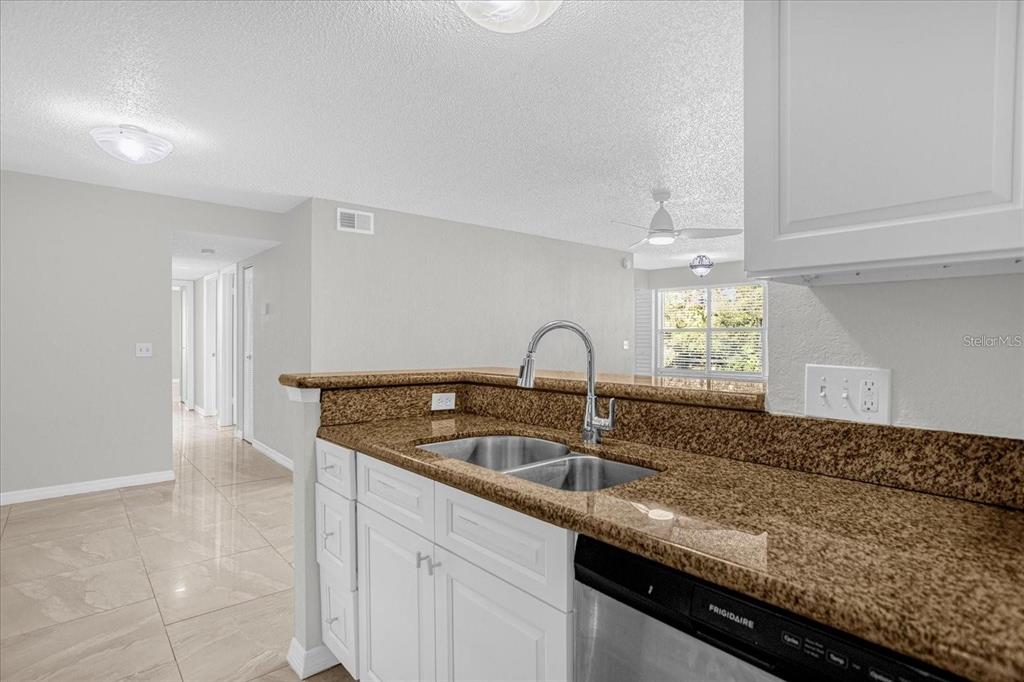 A kitchen with white cabinets, granite countertops, and a stainless steel dishwasher — 5132 CONROY ROAD UNIT 928, ORLANDO, FL