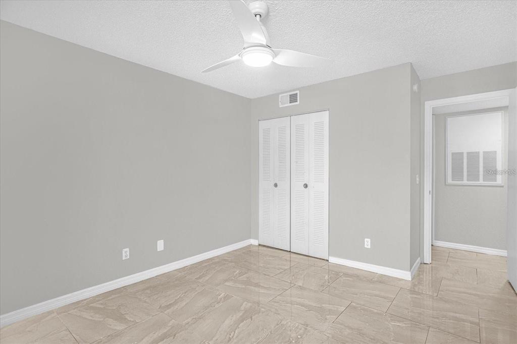 A bedroom with light gray walls, white louvered closet doors, and beige tile flooring — 5132 CONROY ROAD UNIT 928, ORLANDO, FL
