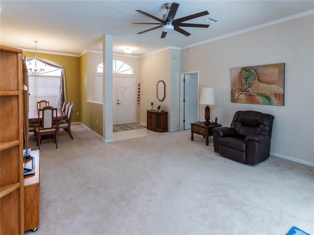 A living room with beige carpet, a brown leather recliner, and an adjacent dining area — 12202 ROSELAND DRIVE, NEW PORT RICHEY, FL