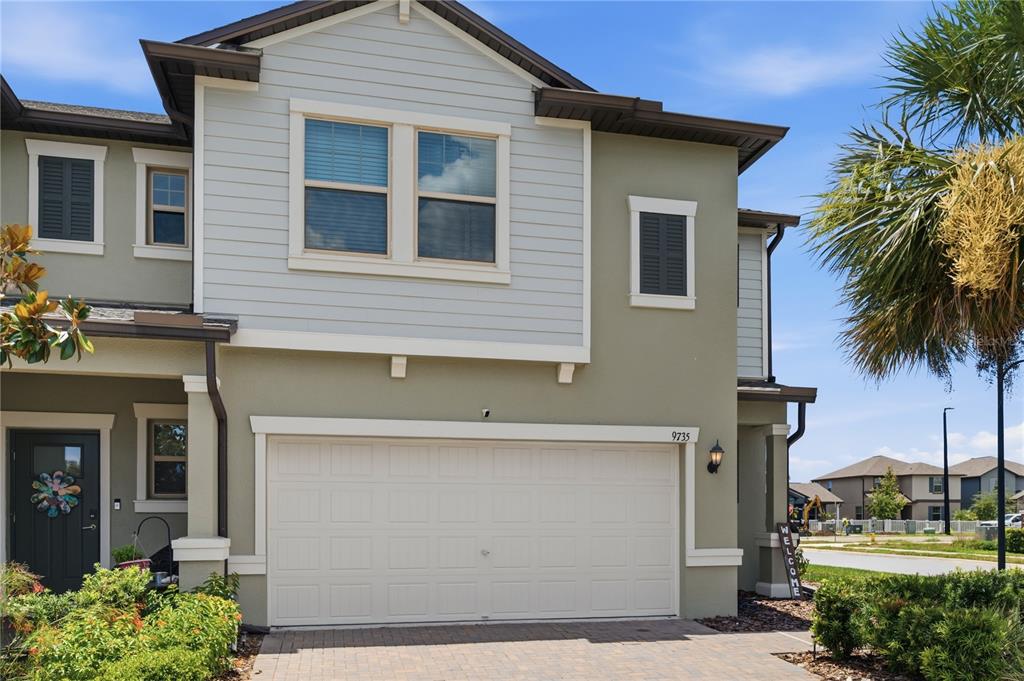 A two-story townhouse exterior features a beige stucco facade, light gray siding, and a garage — 9735 ASHWORTH PLACE, LAND O LAKES, FL