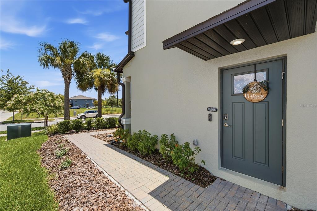 A paved walkway leads to the front entrance of a house with a dark door — 9735 ASHWORTH PLACE, LAND O LAKES, FL