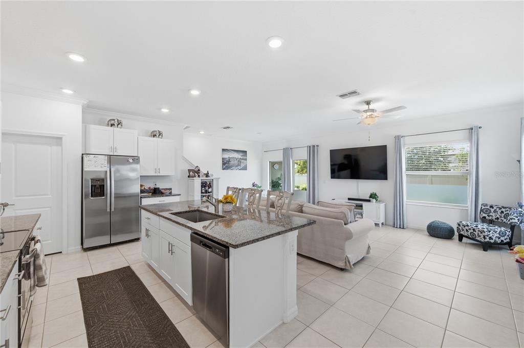 An open-concept kitchen and living area featuring white cabinets, granite countertops, and tile flooring — 9735 ASHWORTH PLACE, LAND O LAKES, FL