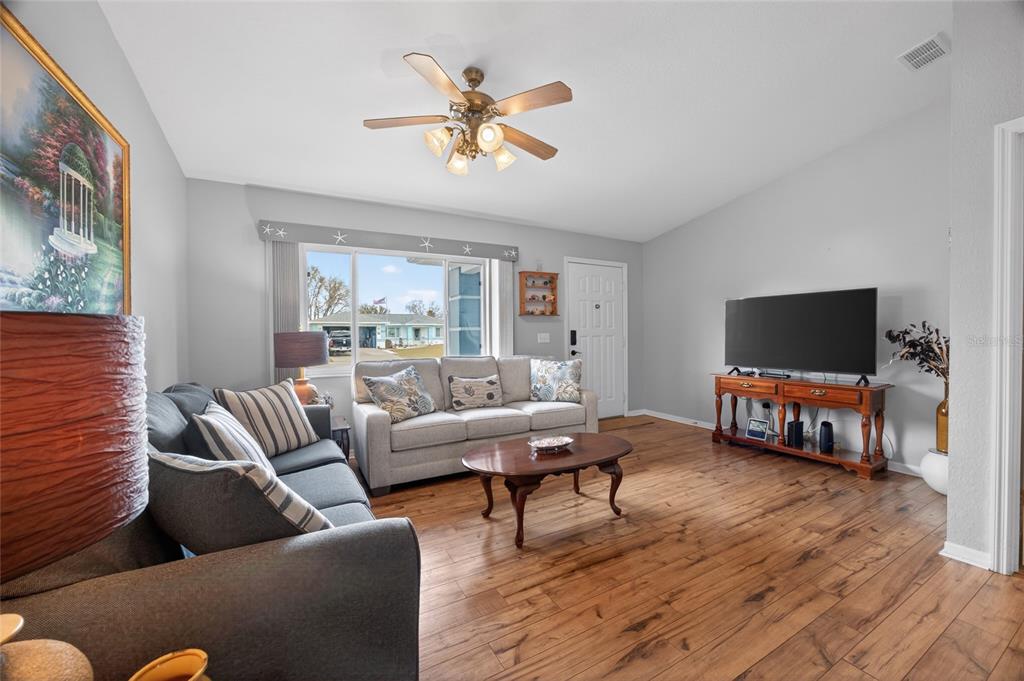 A living room features a gray sofa, a light-colored sofa, a coffee table, and wood flooring — 6196 SW 101ST PLACE, OCALA, FL