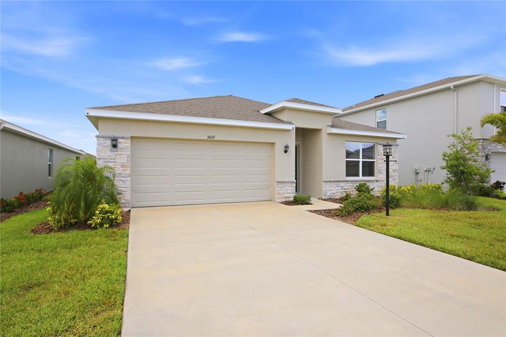 A single-story house with a beige stucco exterior, stone accents, and a two-car garage — 3659 HATCHERY WAY, BRADENTON, FL