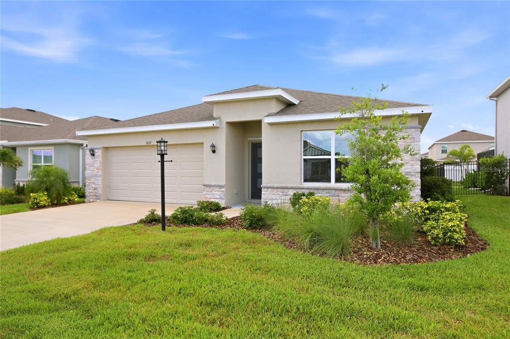 A single-story house with a beige stucco exterior, stone accents, and a two-car garage — 3659 HATCHERY WAY, BRADENTON, FL