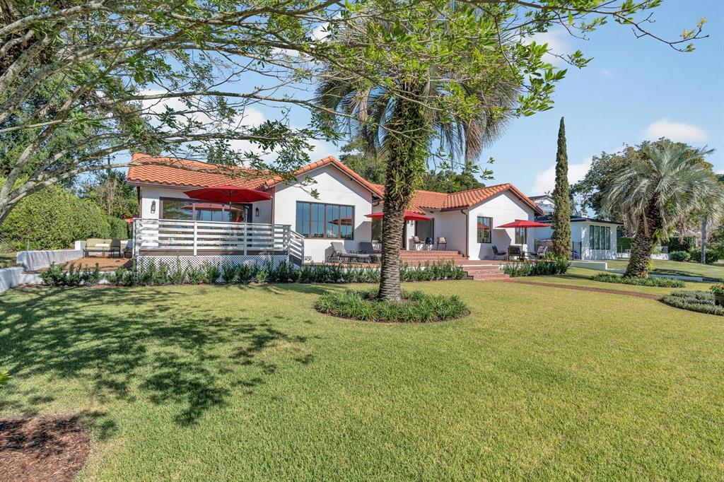 A white house with a red tile roof features a large lawn and palm trees — 631 LAKE CATHERINE DRIVE, MAITLAND, FL