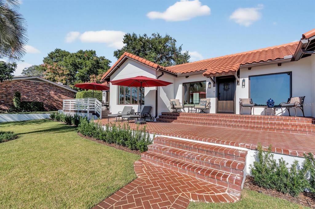 A red brick patio with steps leads to a white house with a tile roof — 631 LAKE CATHERINE DRIVE, MAITLAND, FL