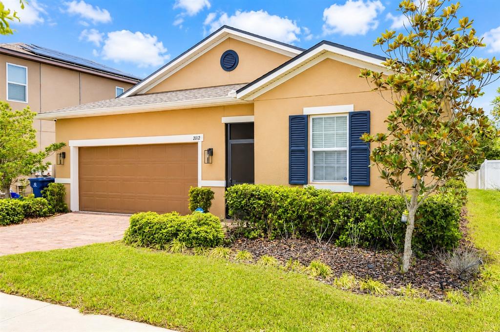 A tan single-story house with a two-car garage, blue shutters, and a landscaped front yard — 2012 SLOANS OUTLOOK DRIVE, GROVELAND, FL