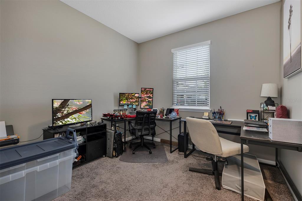 A home office features two desks, multiple computer monitors, and a large storage bin — 2012 SLOANS OUTLOOK DRIVE, GROVELAND, FL