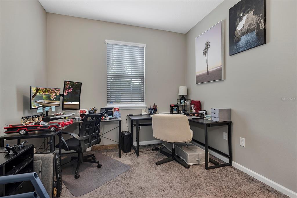 A home office features two black desks, two chairs, dual monitors, and wall art — 2012 SLOANS OUTLOOK DRIVE, GROVELAND, FL