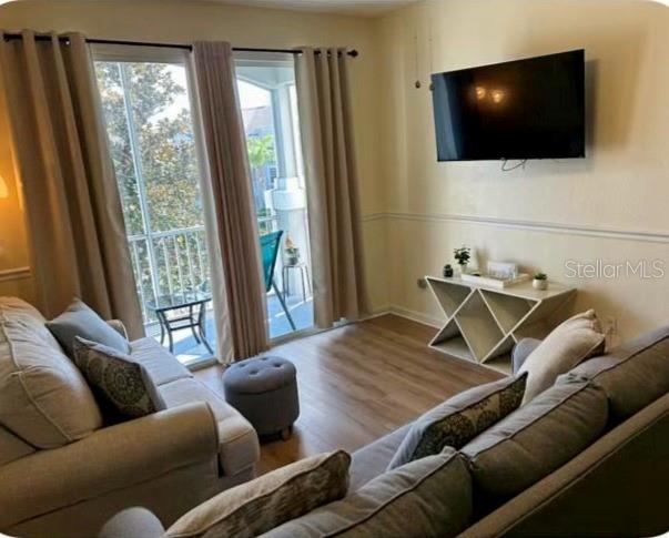 A living room features light-colored sofas, a wall-mounted television, and a sliding glass door — 8107 COCONUT PALM WAY UNIT 201, KISSIMMEE, FL