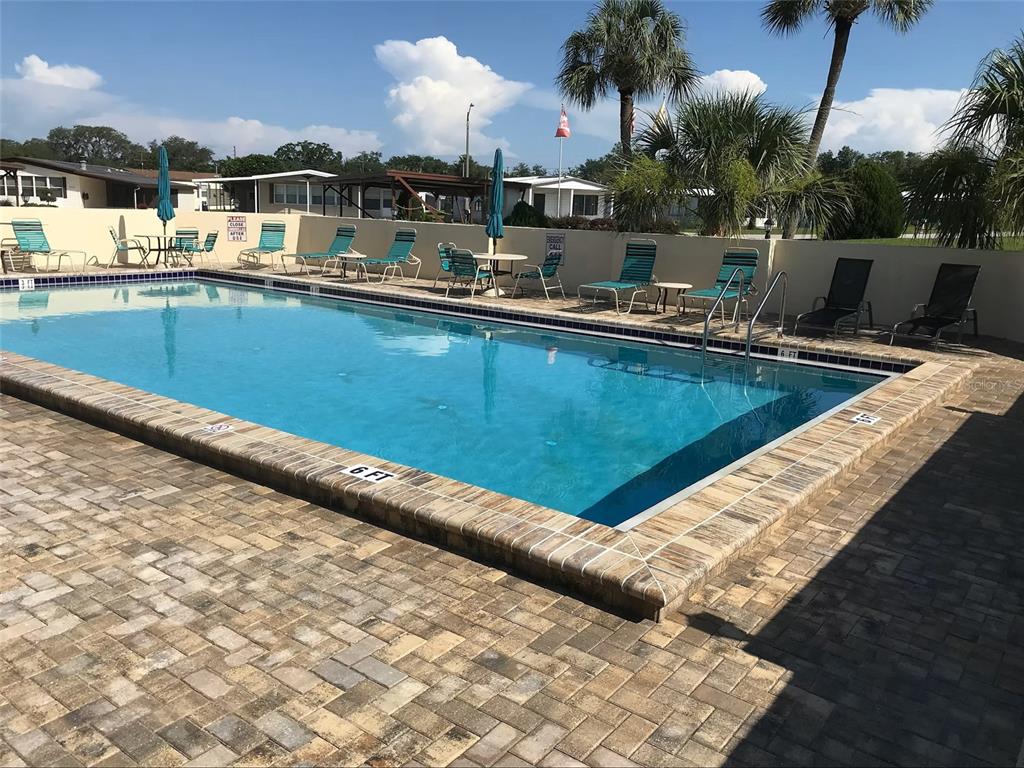 An outdoor swimming pool with a brick paver deck and lounge chairs — 35801 BRISA DRIVE, ZEPHYRHILLS, FL