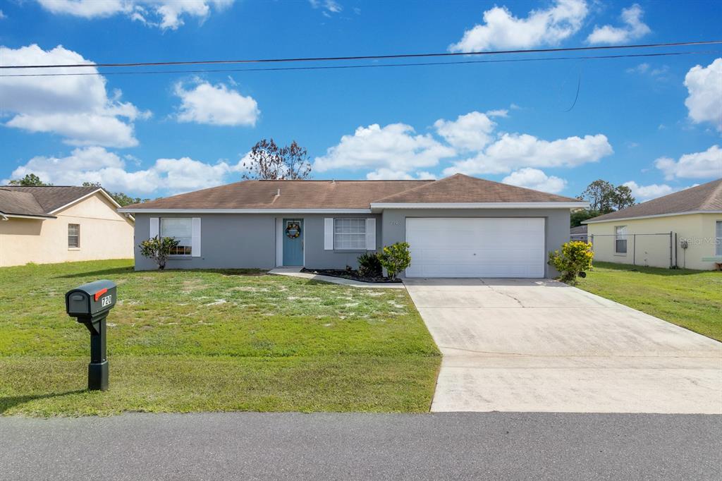 A single-story gray house with a two-car garage and a blue front door — 719 DEL RAY DRIVE, KISSIMMEE, FL