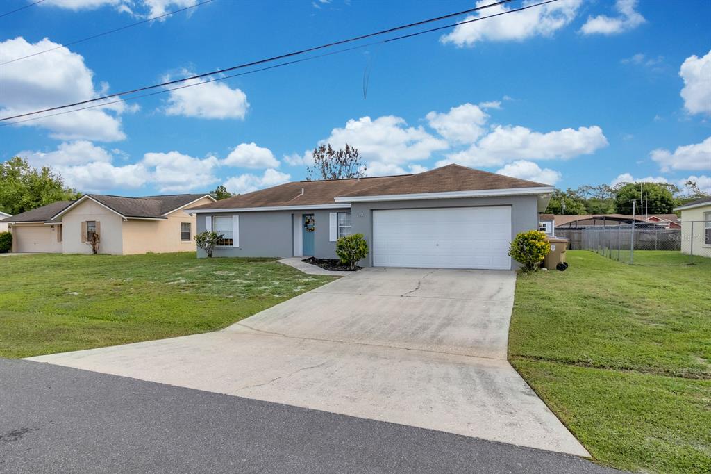 A single-story gray house with a white garage door and a concrete driveway — 719 DEL RAY DRIVE, KISSIMMEE, FL