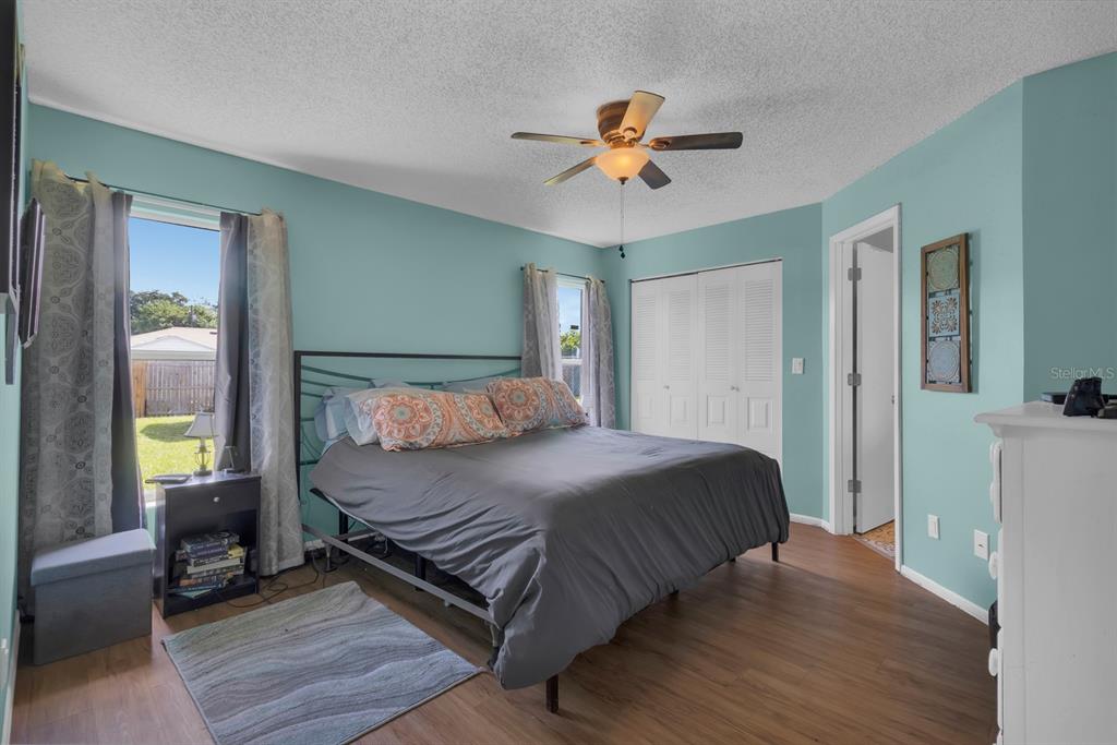 A bedroom with light blue walls, a ceiling fan, a bed, and wood-look flooring — 719 DEL RAY DRIVE, KISSIMMEE, FL