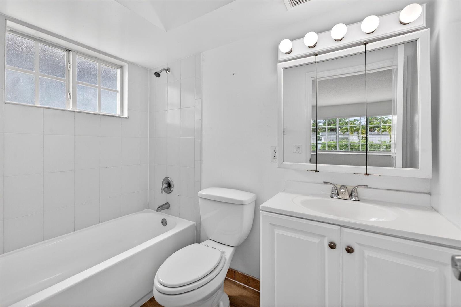 A bathroom features a white vanity, a toilet, and a bathtub with a shower head — 3380 NE 16th Terrace Unit 3, Pompano Beach FL 33064, POMPANO BEACH, FL