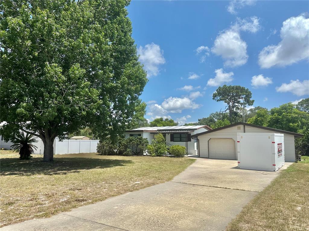 A single-story house with a two-car garage and a front yard under a blue sky — 9702 ANDY DRIVE, HUDSON, FL