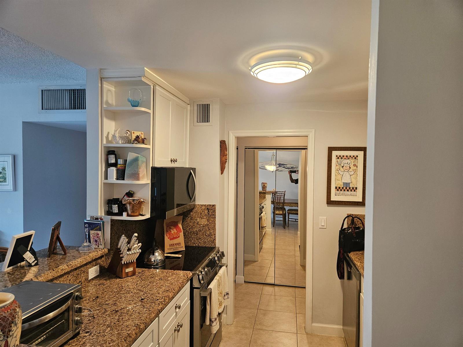 A kitchen features granite countertops, white cabinetry, a microwave, and a stainless steel stove — 2121 N Ocean Boulevard N # 405e, Boca Raton FL 33431, BOCA RATON, FL