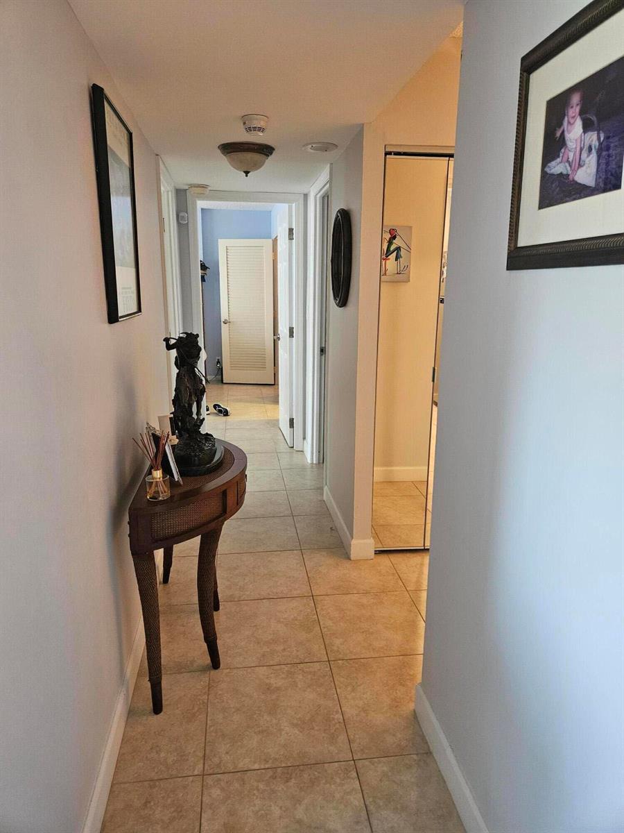 A hallway with tile floors, a semi-circular wooden console table, and framed wall art — 2121 N Ocean Boulevard N # 405e, Boca Raton FL 33431, BOCA RATON, FL