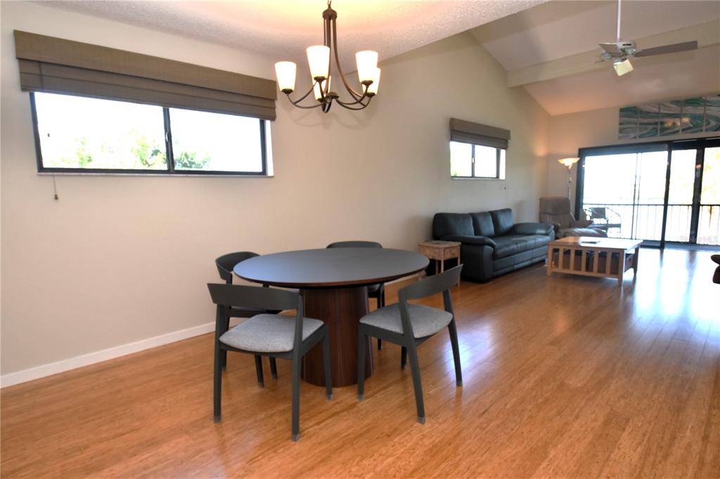 A dining area with a round table and chairs sits in an open-concept living space — 1601 BAYHOUSE POINT DRIVE UNIT BA201, SARASOTA, FL