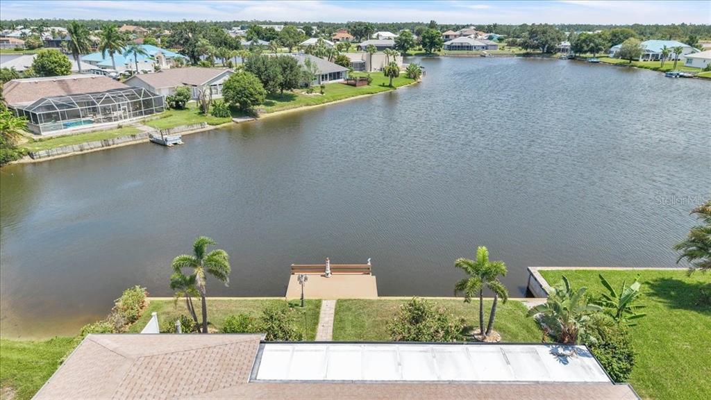 An aerial view shows a backyard with a dock extending into a large lake — 11614 SW COURTLY MANOR DRIVE, LAKE SUZY, FL