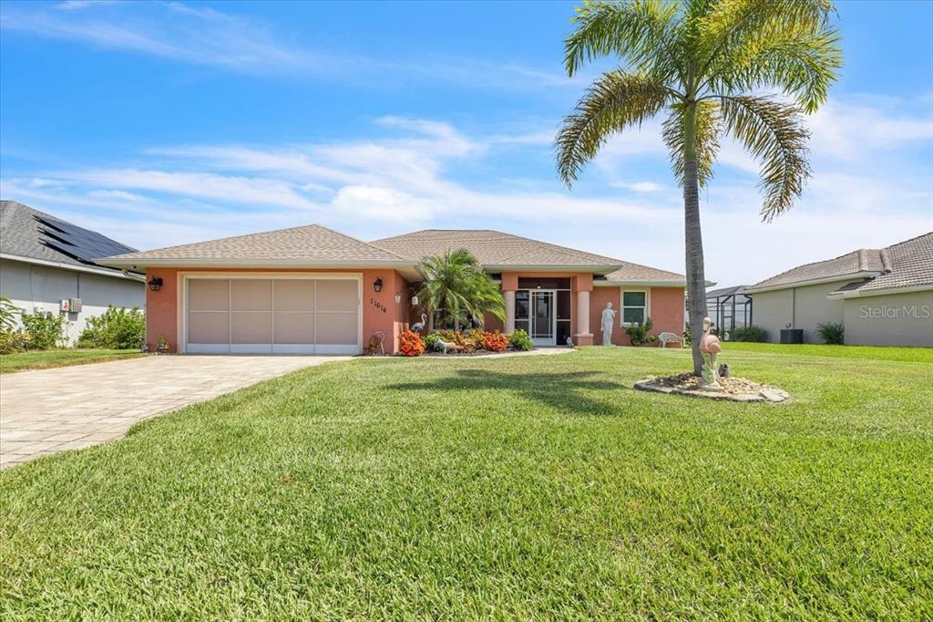 A single-story peach-colored house with a palm tree and a paved driveway — 11614 SW COURTLY MANOR DRIVE, LAKE SUZY, FL