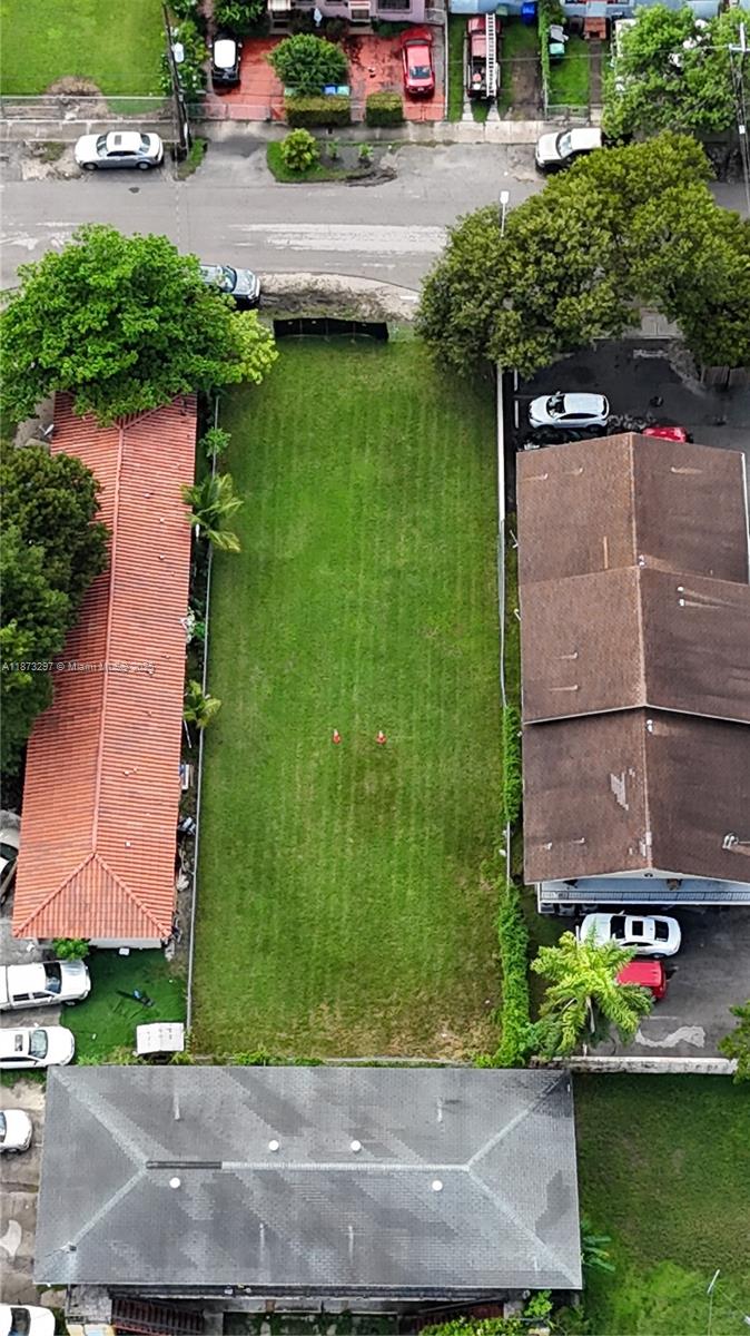 An aerial view shows a vacant rectangular grass lot situated between two residential properties — 1941 NW 19th Ave, Miami FL 33125, MIAMI, FL