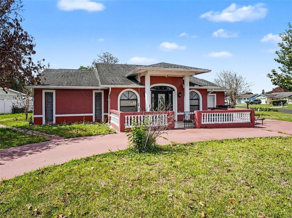 A red single-story house features a covered front porch with white railings and columns — 151 TULPAN DRIVE, KISSIMMEE, FL