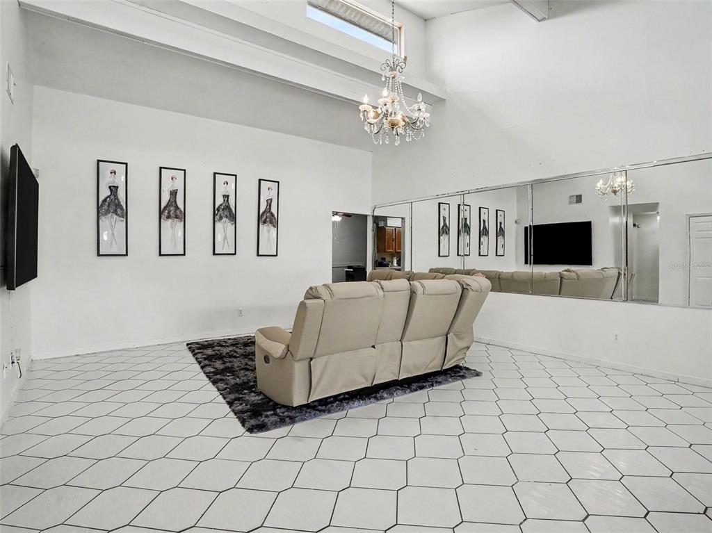 A living room features white hexagonal floor tiles, a beige reclining sofa, and mirrored walls — 151 TULPAN DRIVE, KISSIMMEE, FL