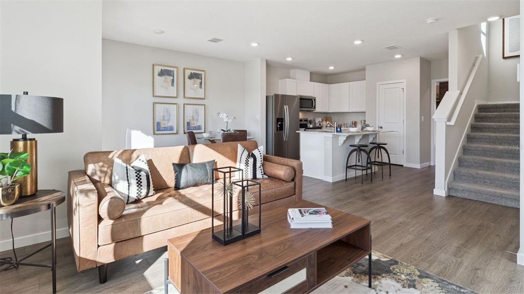 A living room with a brown leather sofa, coffee table, and an open-concept kitchen — 284 PRESTON COVE DRIVE, ST CLOUD, FL