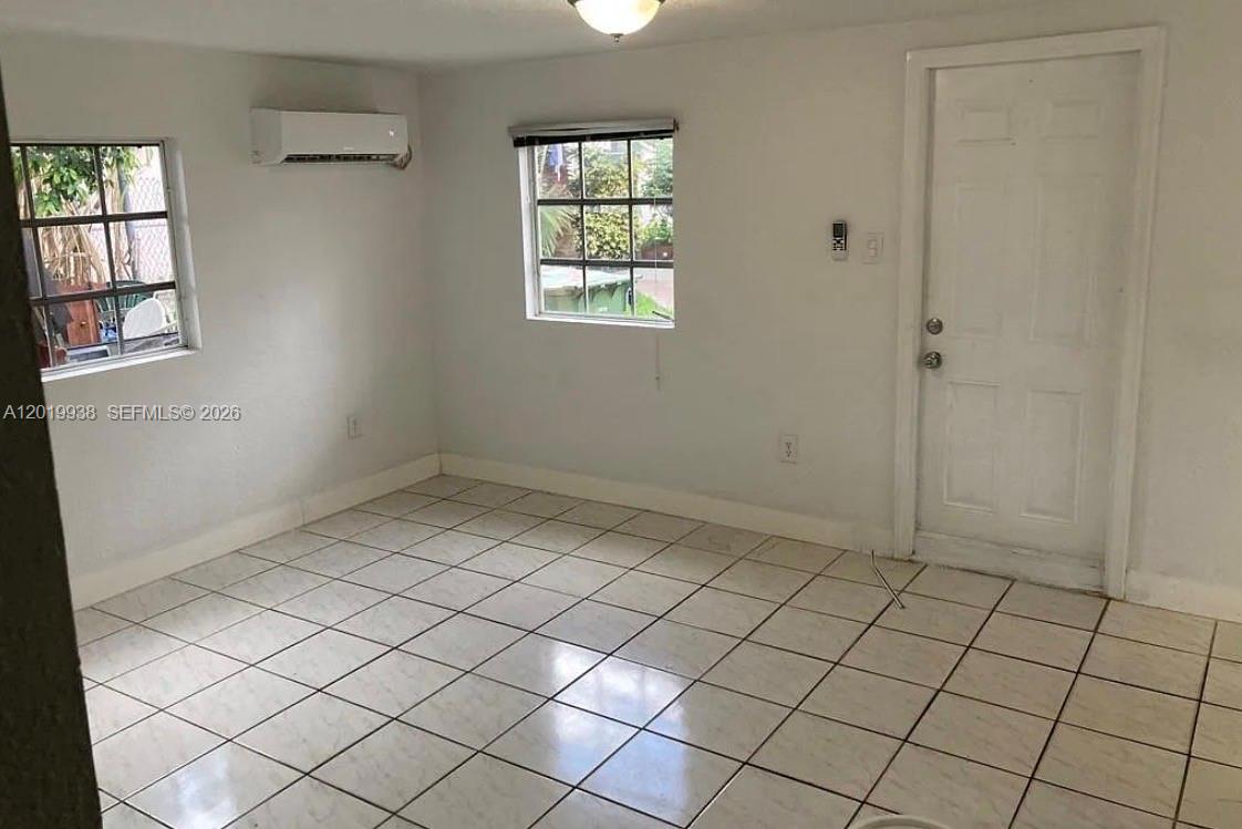 A room with white walls, tiled floors, two windows, and a white door — 141 W 26th St, Hialeah FL 33010, HIALEAH, FL