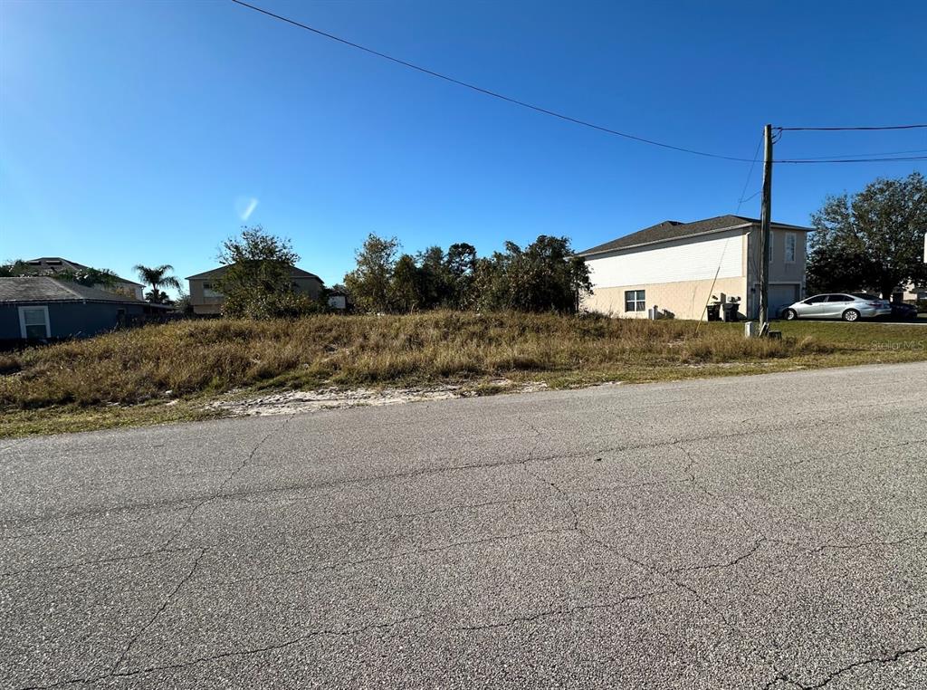 A vacant, grassy residential lot sits between two houses along a paved street — 61 SAWFISH COURT, KISSIMMEE, FL