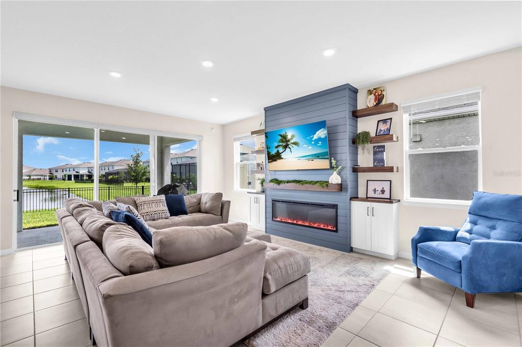 A living room features a blue shiplap fireplace wall, a gray sectional, and a blue armchair — 18015 FATTORIA TERRACE, LAKEWOOD RANCH, FL