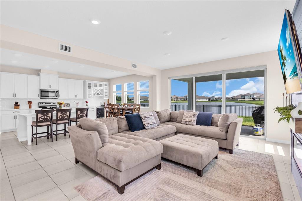 A living room features a blue shiplap fireplace wall, floating shelves, and a large sectional — 18015 FATTORIA TERRACE, LAKEWOOD RANCH, FL
