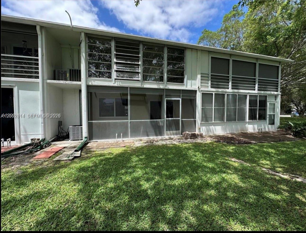 The exterior of a two-story building features a screened-in patio and large windows — 2 Tilford A # 2, Deerfield Beach FL 33442, DEERFIELD BEACH, FL