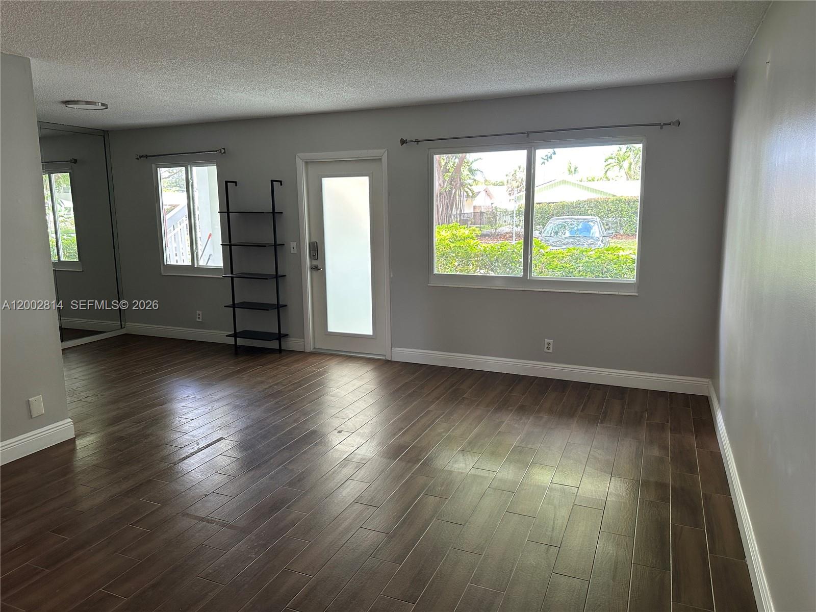 A living room features gray walls, dark wood-look tile flooring, a glass-paneled door, and windows — 2 Tilford A # 2, Deerfield Beach FL 33442, DEERFIELD BEACH, FL