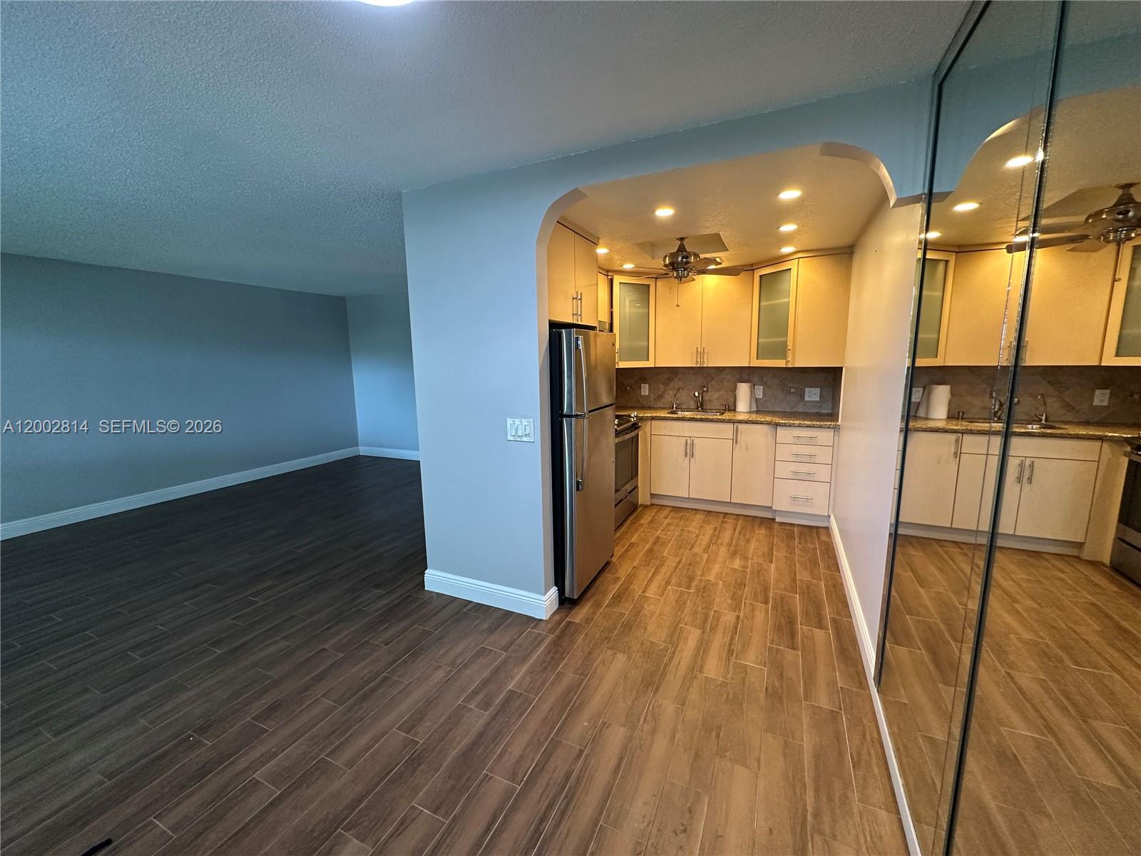 A kitchen with light wood cabinets and stainless steel appliances sits beside a living area — 2 Tilford A # 2, Deerfield Beach FL 33442, DEERFIELD BEACH, FL
