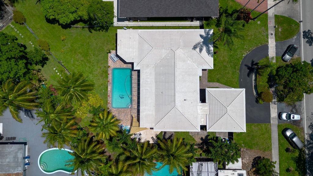 An aerial view shows a house with a white roof, a swimming pool, and palm trees — 19885 NE 22nd Avenue, Miami FL 33180, MIAMI, FL