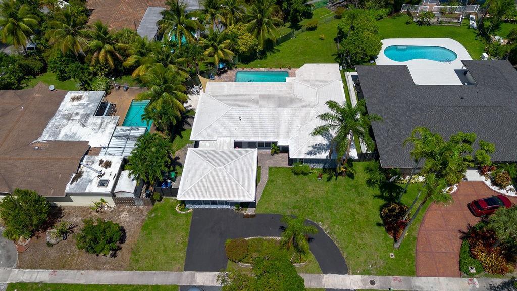 An aerial view shows a house with a white roof, a pool, and a driveway — 19885 NE 22nd Avenue, Miami FL 33180, MIAMI, FL