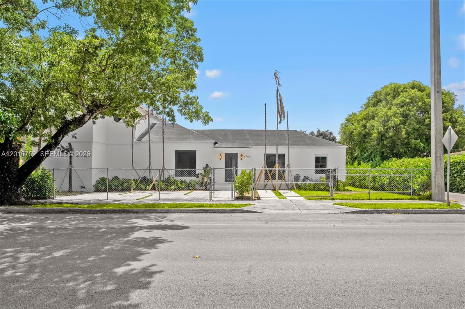A white single-story house with a chain-link fence sits behind a paved driveway — 4746 NW 10th Ave, Miami FL 33127, MIAMI, FL
