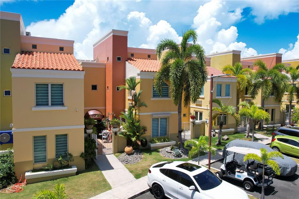 A multi-story residential building with yellow stucco walls, terracotta roof tiles, and palm trees — 46 AQUABELLA UNIT 46, HUMACAO, PR