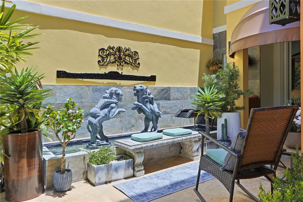 A patio features a stone water fountain with two animal statues, seating, and potted plants — 46 AQUABELLA UNIT 46, HUMACAO, PR