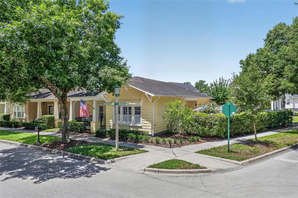 A yellow single-story house with a front porch sits on a corner lot with trees — 920 PAWSTAND ROAD, CELEBRATION, FL