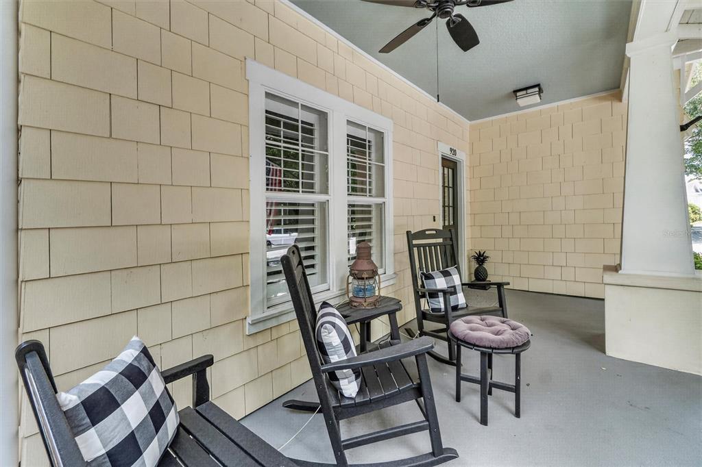 A covered porch features light yellow shingle siding, black rocking chairs, and a ceiling fan — 920 PAWSTAND ROAD, CELEBRATION, FL