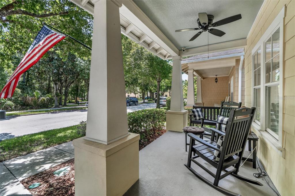 A covered front porch features rocking chairs, a ceiling fan, and an American flag — 920 PAWSTAND ROAD, CELEBRATION, FL